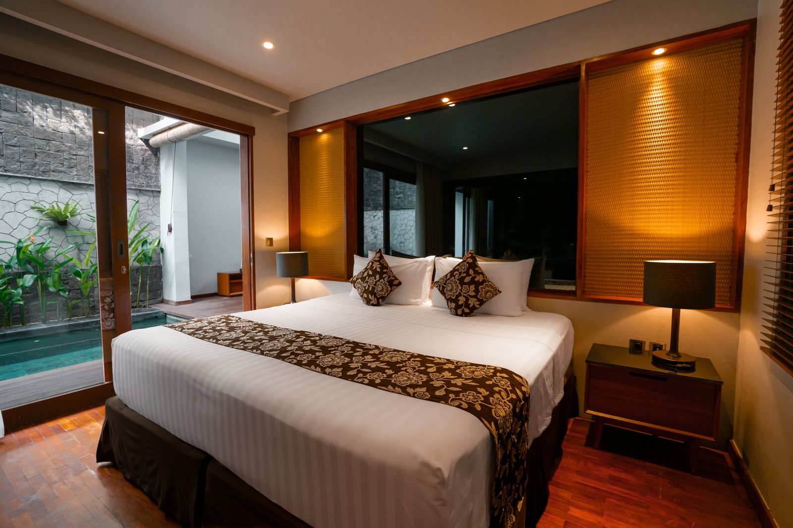 Exterior wide-angle shot of the hotel facade showing a guest relaxing on a private balcony from a distance.