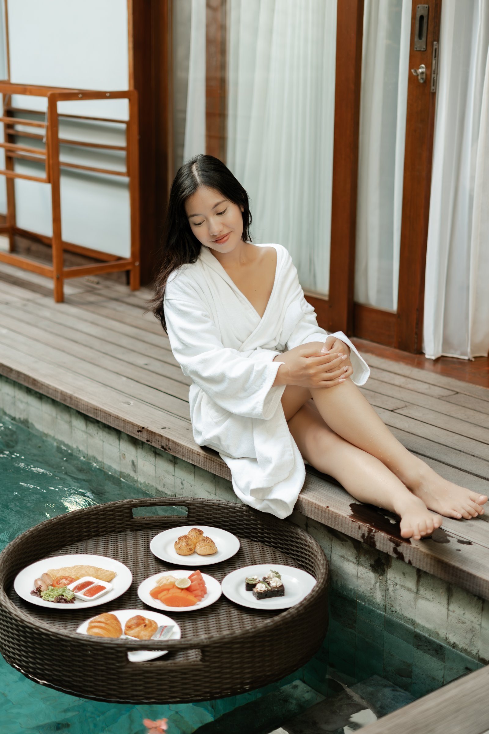 Exterior wide-angle shot of the hotel facade showing a guest relaxing on a private balcony from a distance.
