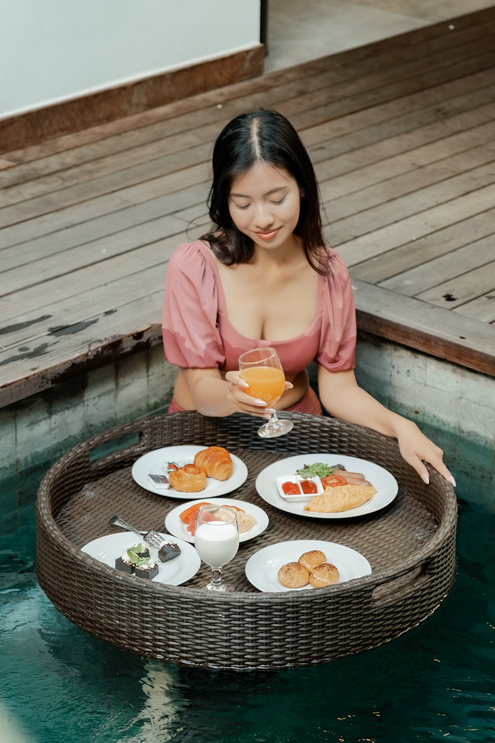 Exterior wide-angle shot of the hotel facade showing a guest relaxing on a private balcony from a distance.