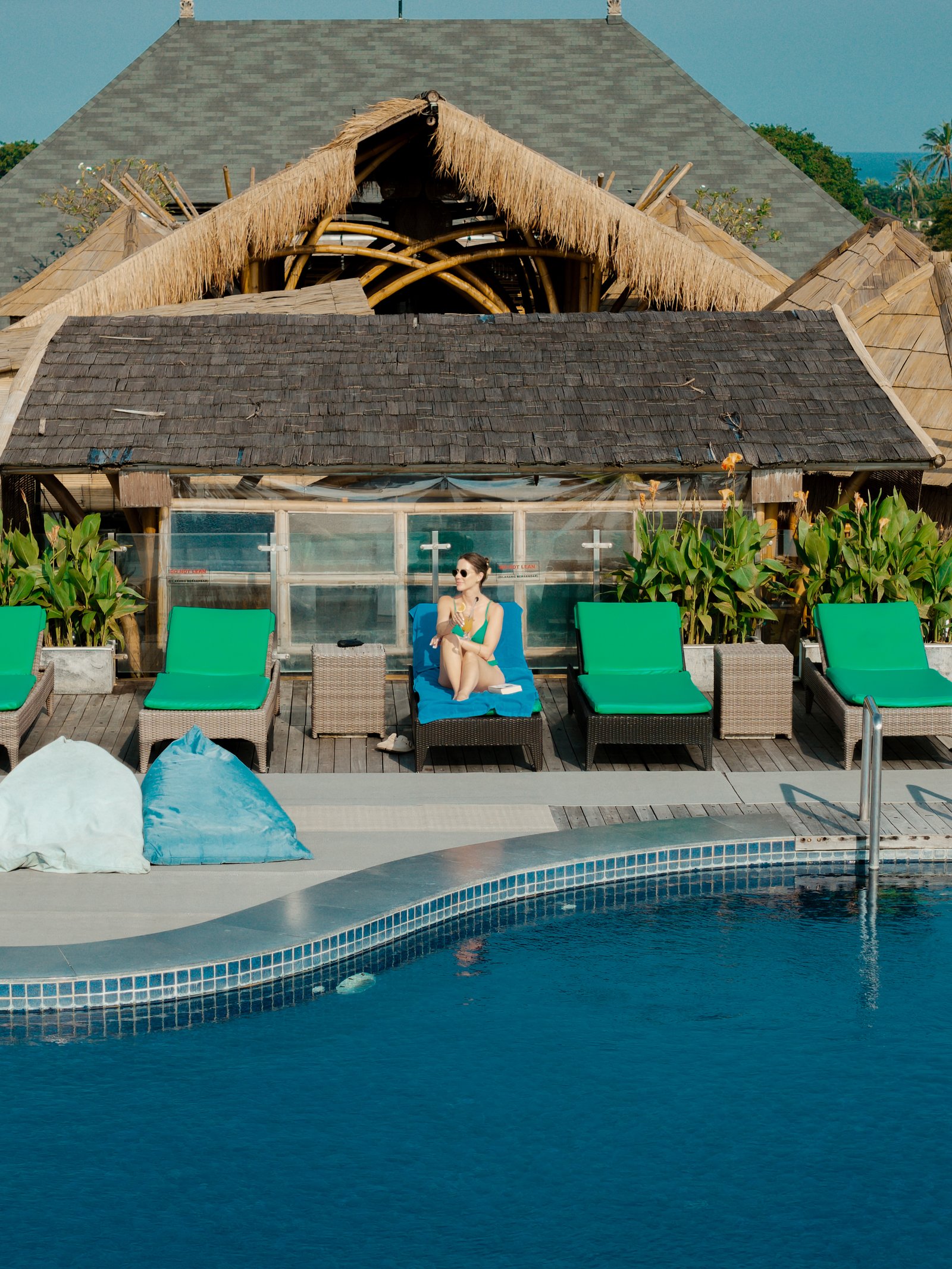 Exterior wide-angle shot of the hotel facade showing a guest relaxing on a private balcony from a distance.